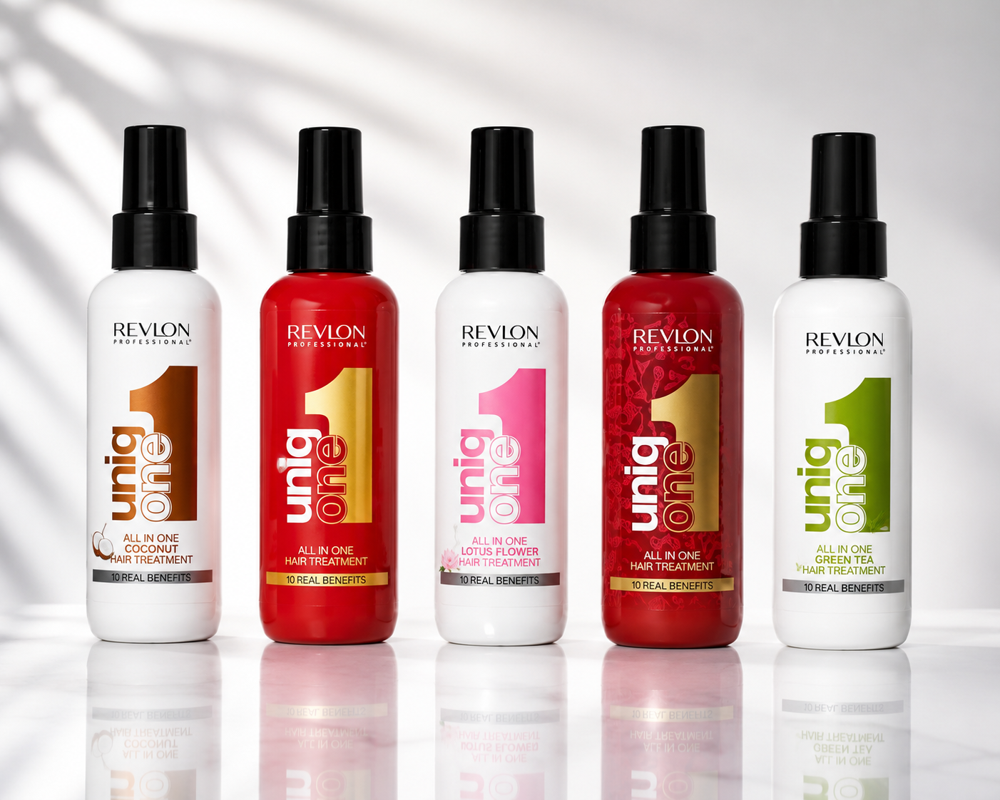 Premium product image featuring the Revlon Uniq One hair treatment range displayed on a reflective surface with clean studio lighting, showcasing multiple variants in a sleek professional salon aesthetic.