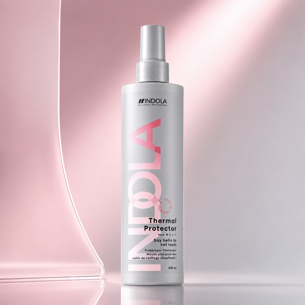 Indola Thermal Protector spray on a soft pink gradient background with sleek glass-inspired accents.