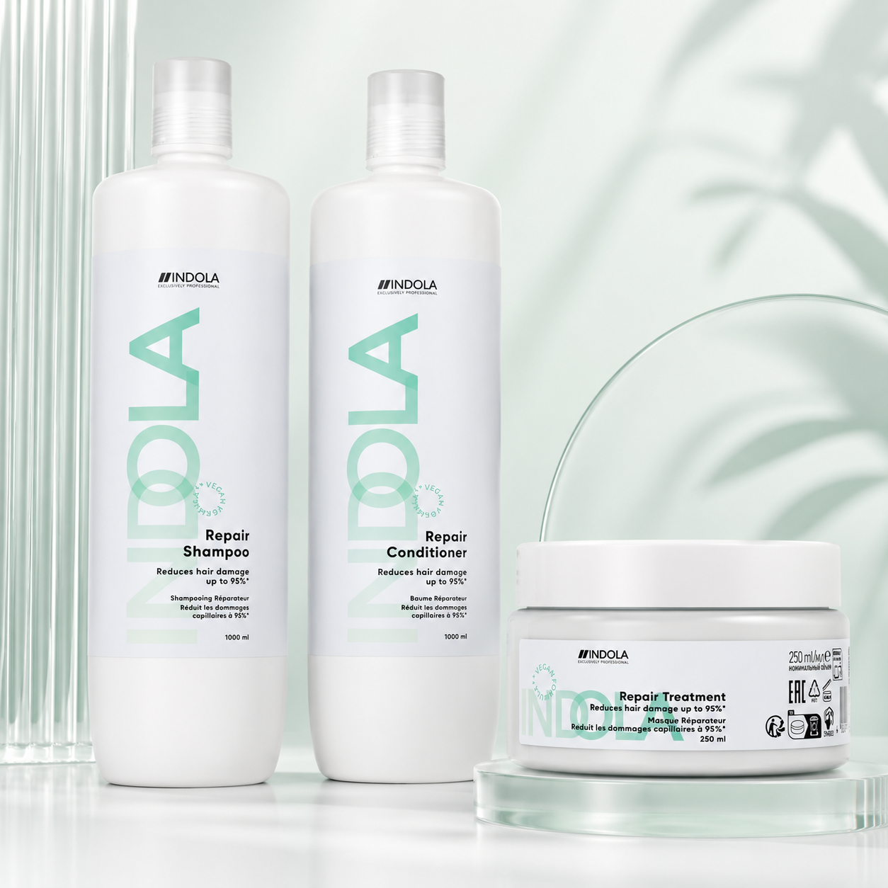 Indola Repair shampoo, conditioner and treatment displayed on a soft mint-green background with sleek glass accents.