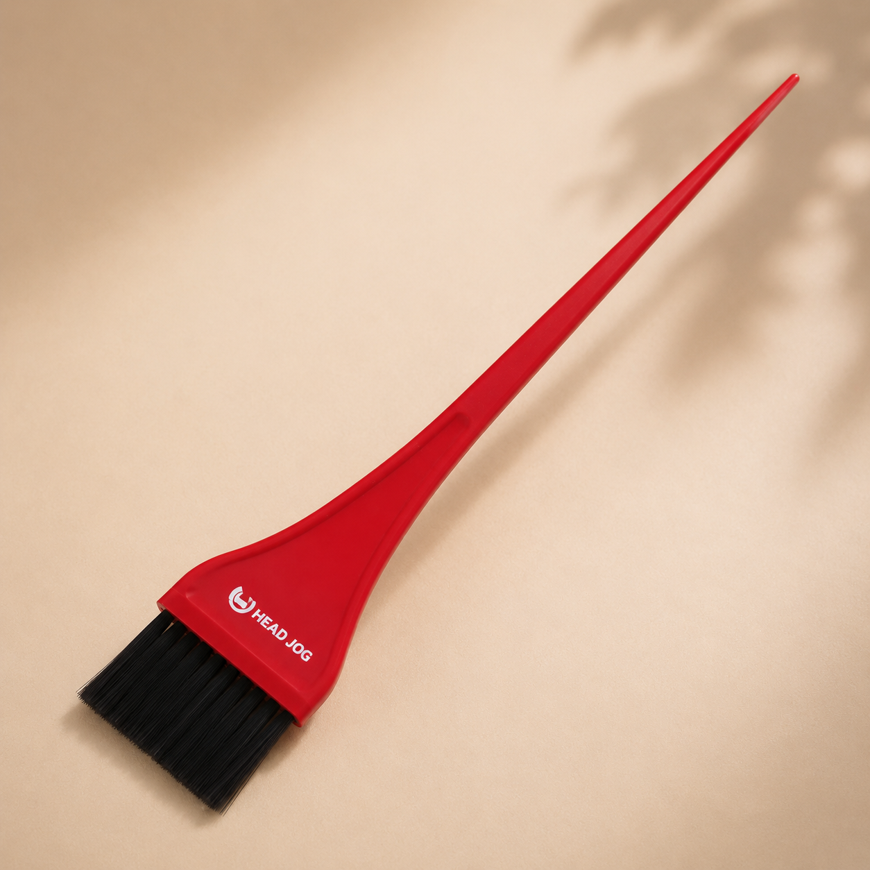 Minimalist collection image featuring a Head Jog red tint brush with black bristles on a soft neutral background.